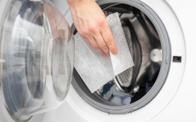 Close up of somebody putting a dryer sheet in a dryer